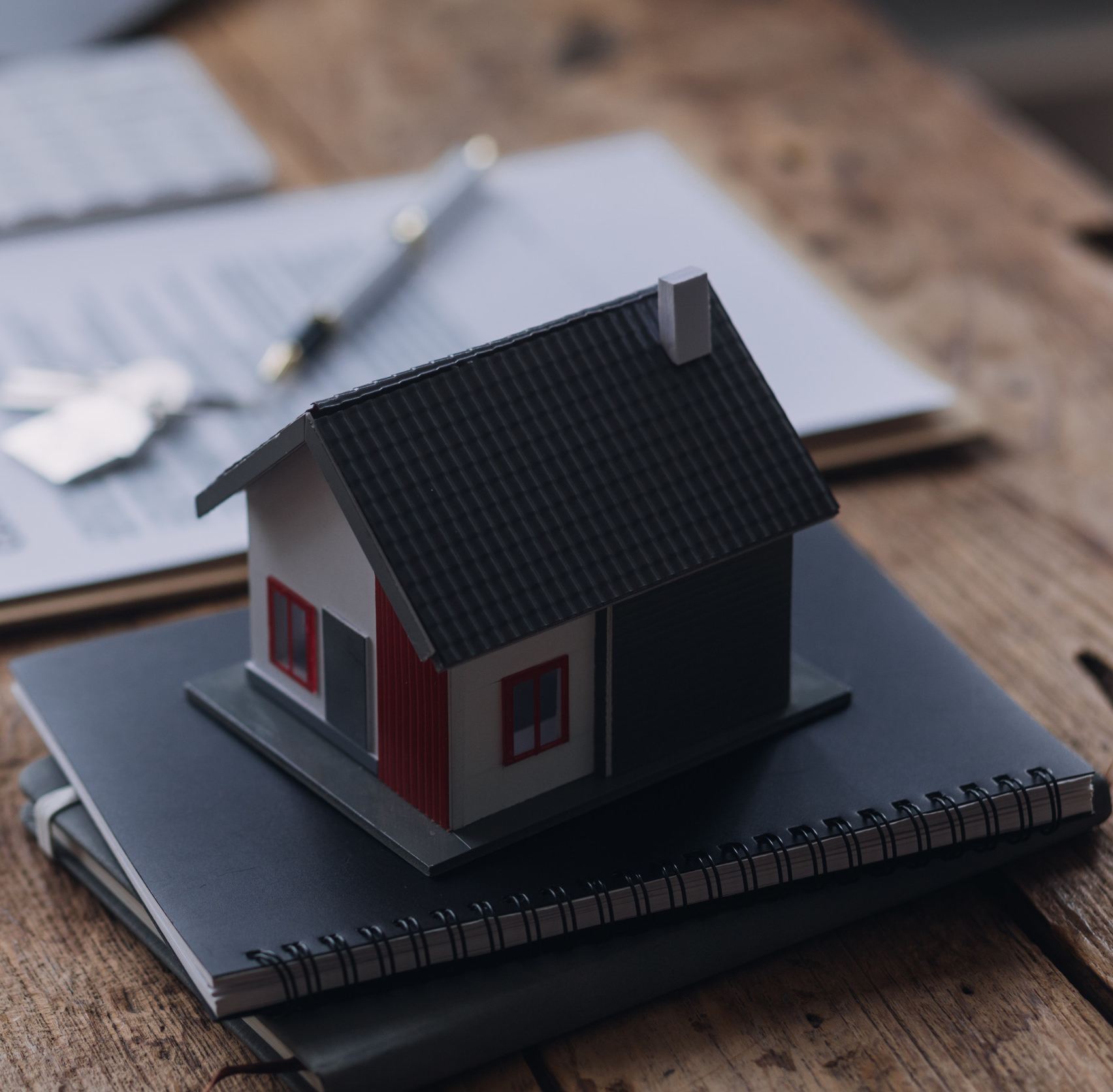 Model house on notebooks, symbolizing homeownership and mortgage services offered by American Liberty Mortgage in Victoria, TX.