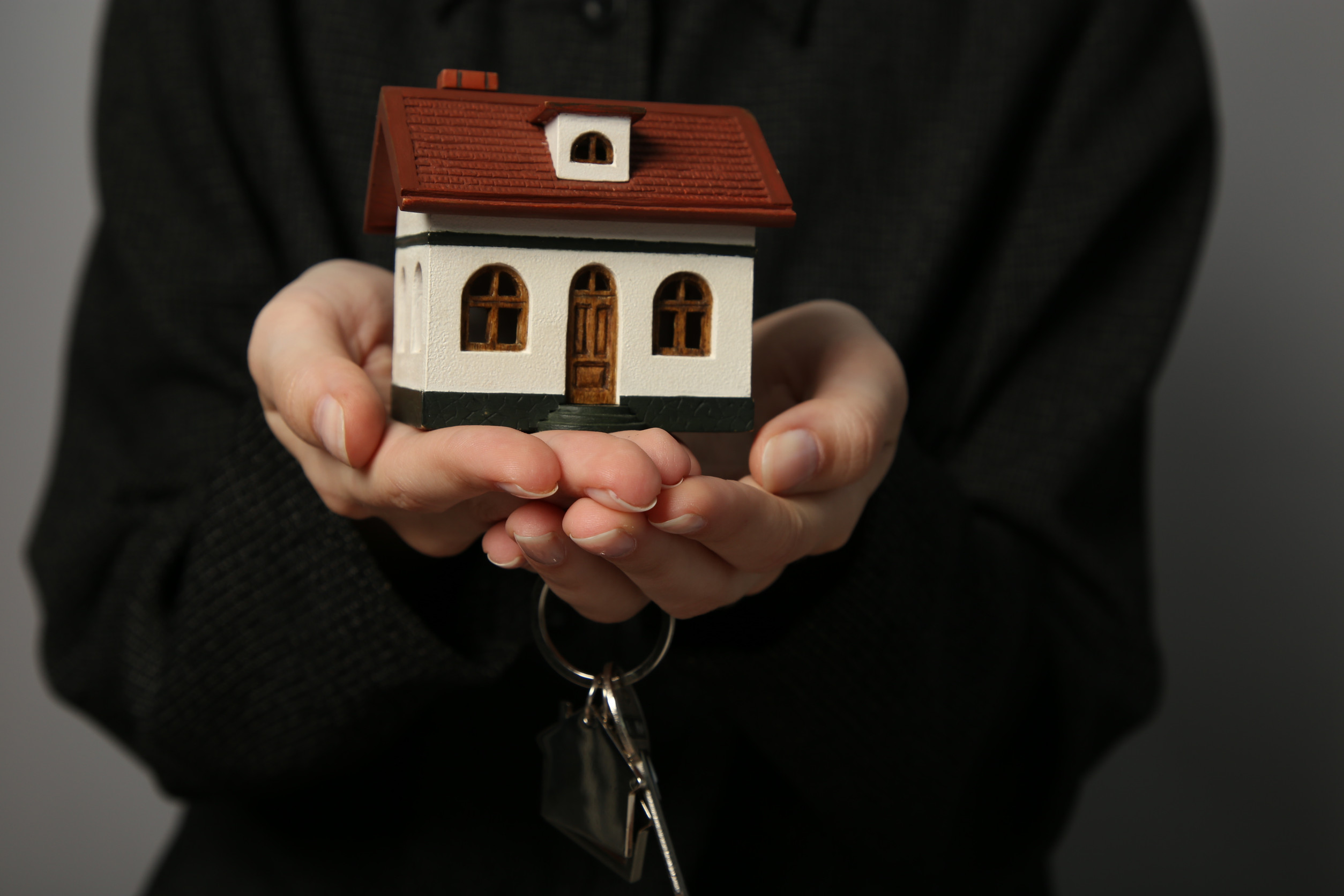 Person holding a small model house and keys, symbolizing homeownership and mortgage options for Victoria homebuyers.
